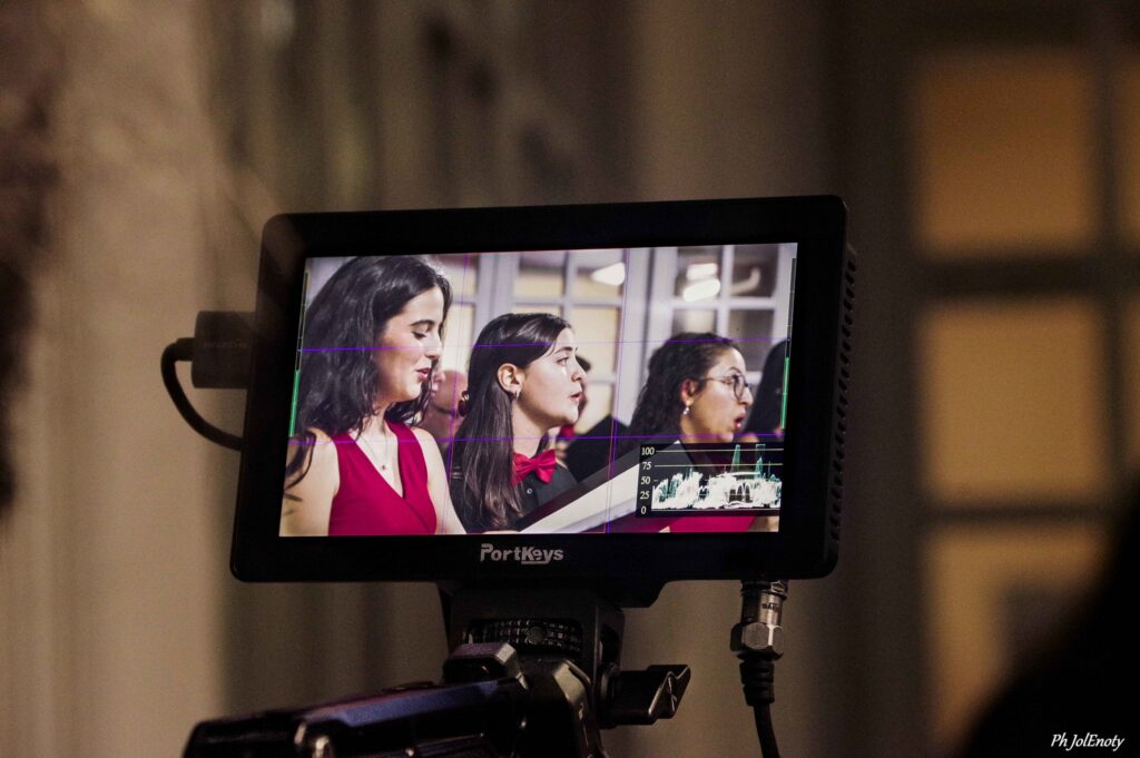 I volti di tre cantanti ripresi sul monitor di una videocamera