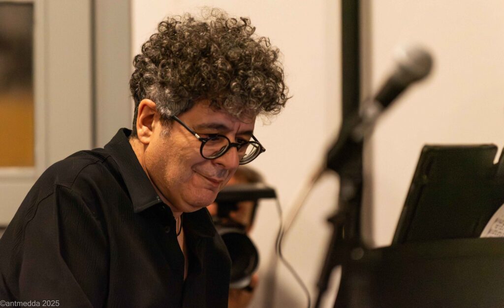 Ritratto di un musicista con occhiali e capelli ricci al pianoforte