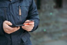 Uomo con smartphone e carta di pagamento in mano