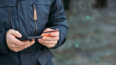 Uomo con smartphone e carta di pagamento in mano