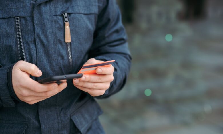 Uomo con smartphone e carta di pagamento in mano