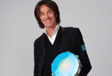 Il cantautore Alberto Fortis sorridente con un tamburello azzurro