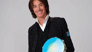 Il cantautore Alberto Fortis sorridente con un tamburello azzurro