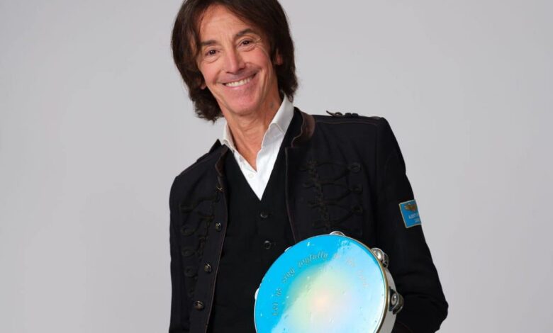 Il cantautore Alberto Fortis sorridente con un tamburello azzurro