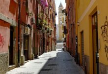 Un vicolo colorato del centro storico di Cagliari con un campanile sullo sfondo