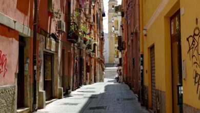 Un vicolo colorato del centro storico di Cagliari con un campanile sullo sfondo