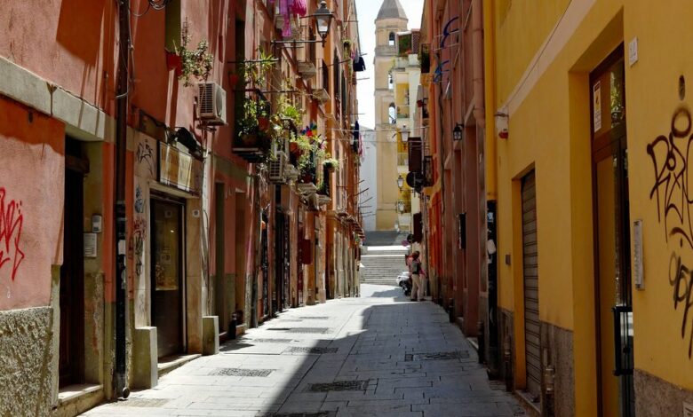 Un vicolo colorato del centro storico di Cagliari con un campanile sullo sfondo