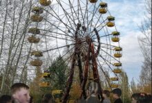 Bambini davanti alla ruota panoramica abbandonata di Pripyat, con una cicogna in volo