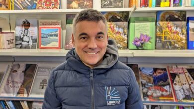 Bachis Medde sorride davanti agli scaffali della sua libreria