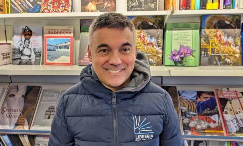 Bachis Medde sorride davanti agli scaffali della sua libreria
