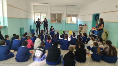 Agenti della Polizia locale di Sassari parlano a una classe di bambini seduti sul pavimento