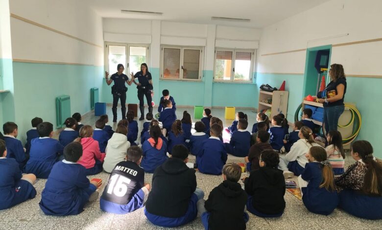Agenti della Polizia locale di Sassari parlano a una classe di bambini seduti sul pavimento